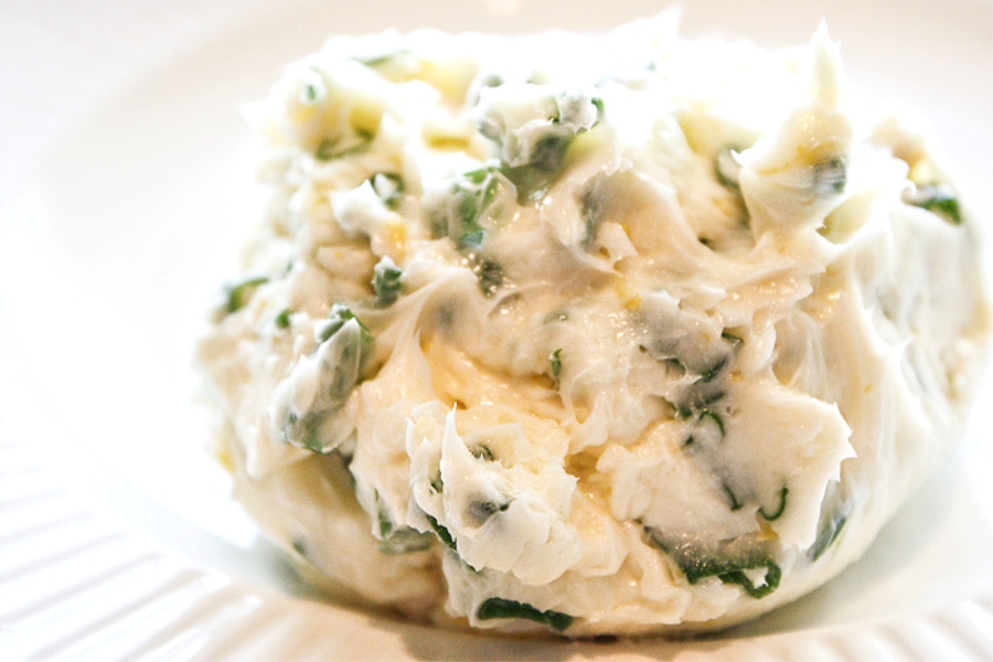 A BALL OF SOFTEN HERB BUTTER MIXED WITH HERBS AND LEMON PEEL