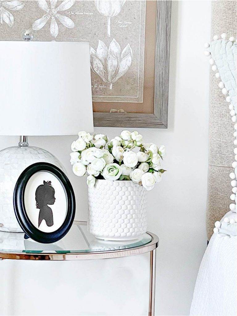 NIGHT STAND IN BEDROOM WITH WHITE FLOWERS ON IT