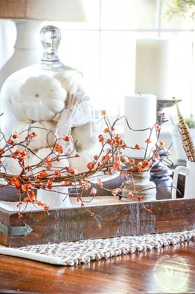 fall vignette with white pumpkins, bittersweet, feathers and candles on wooden candleholders