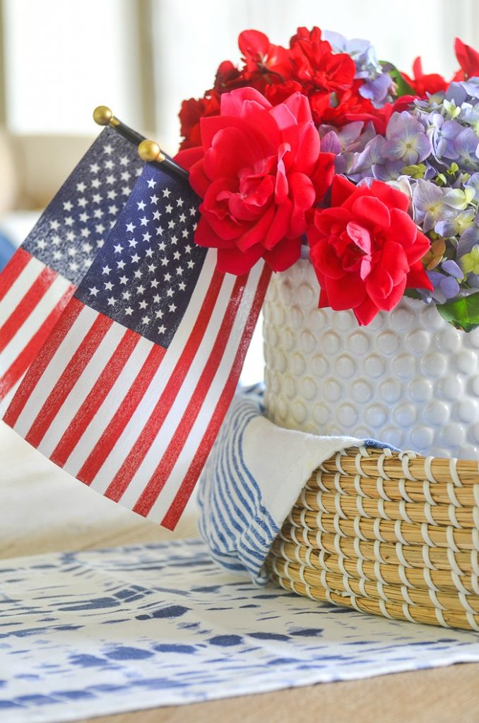 red, white and blue patriotic centerpiece in a basket with two small American flags