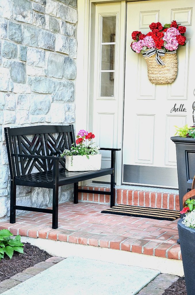 FRONT PORCH WITH BLACK BENCH AND LOTS OF FLOWERS