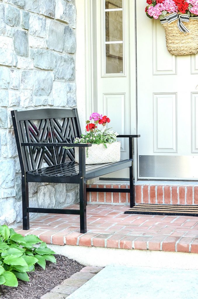 BLACK BENCH ON A SMALL FRONT PORCH