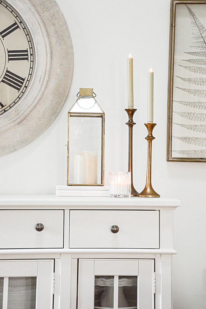 candles and a lantern on a white bookcase