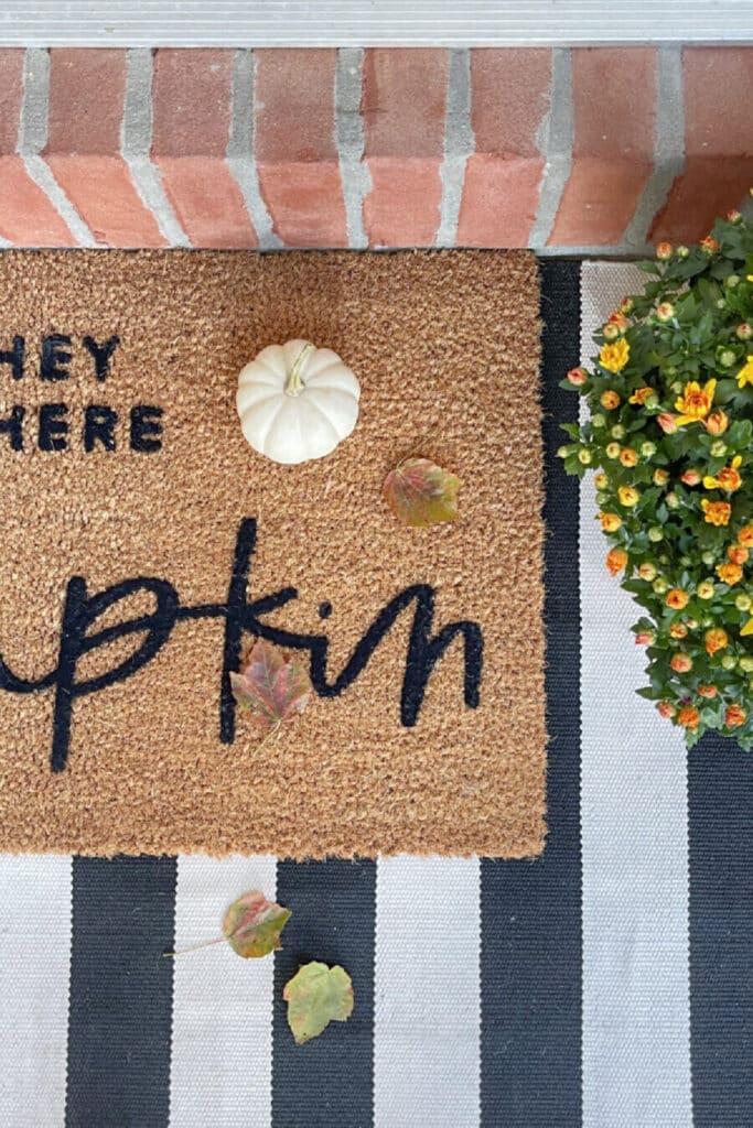 a fall doormat with a little pumpkin on it