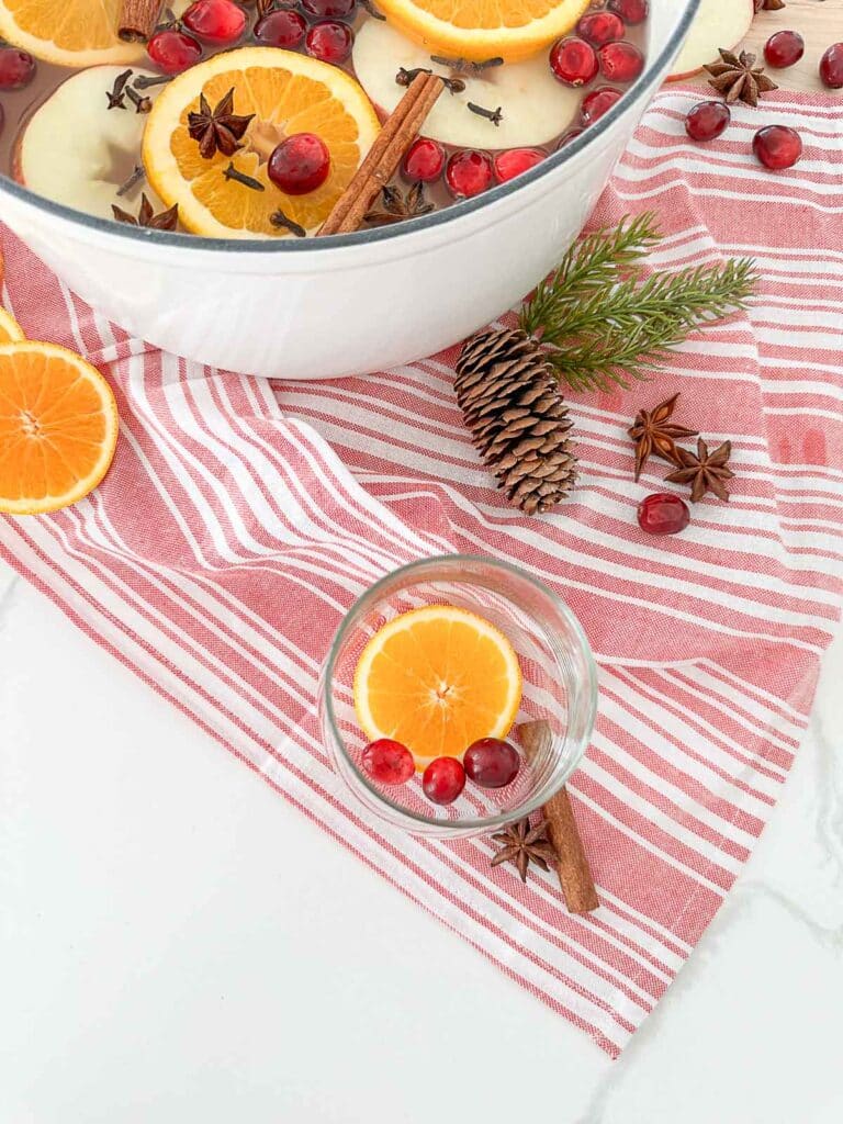 fruit in the bottom of a glass and a pot of mulled cider