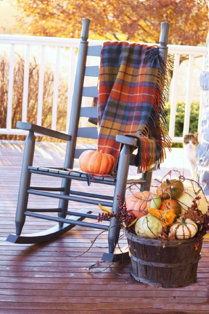 a gray rocker on a porch with a Tartan blanket over it