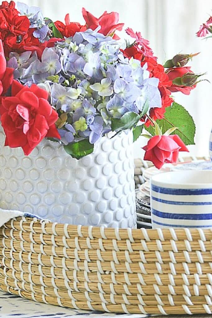 red, white and blue patriotic centerpiece in a basket with two small American flags