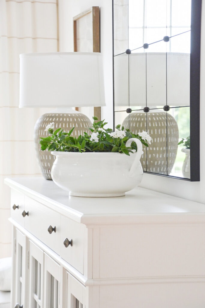 SUMMER HOME TOUR- BEAUTIFUL PERENNIALS PLANTED IN A WHITE PLANTER ON A BUFFET