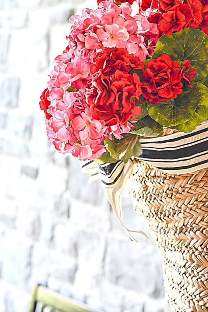 BASKET OF GERANIUMS ON A FRONT PORCH